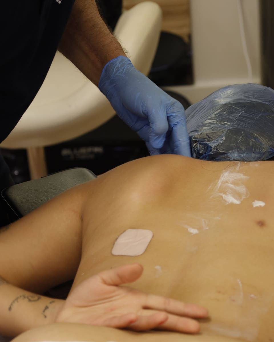 Close view of a gloved clinician's hand palpating a patient's lower back during assessment.