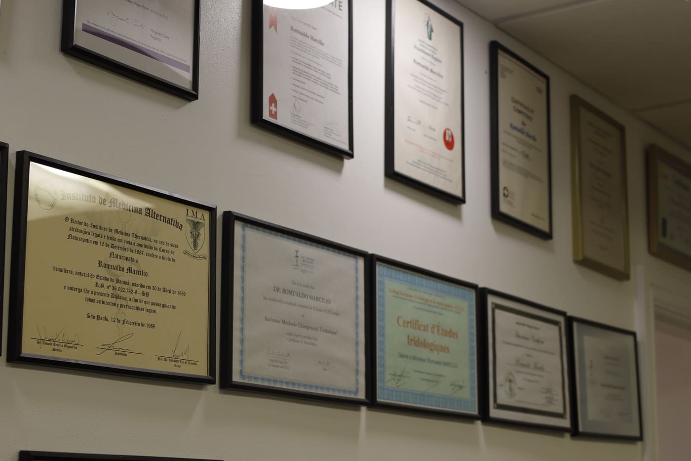 A wall of framed professional certificates and qualifications at PRC Clinic.